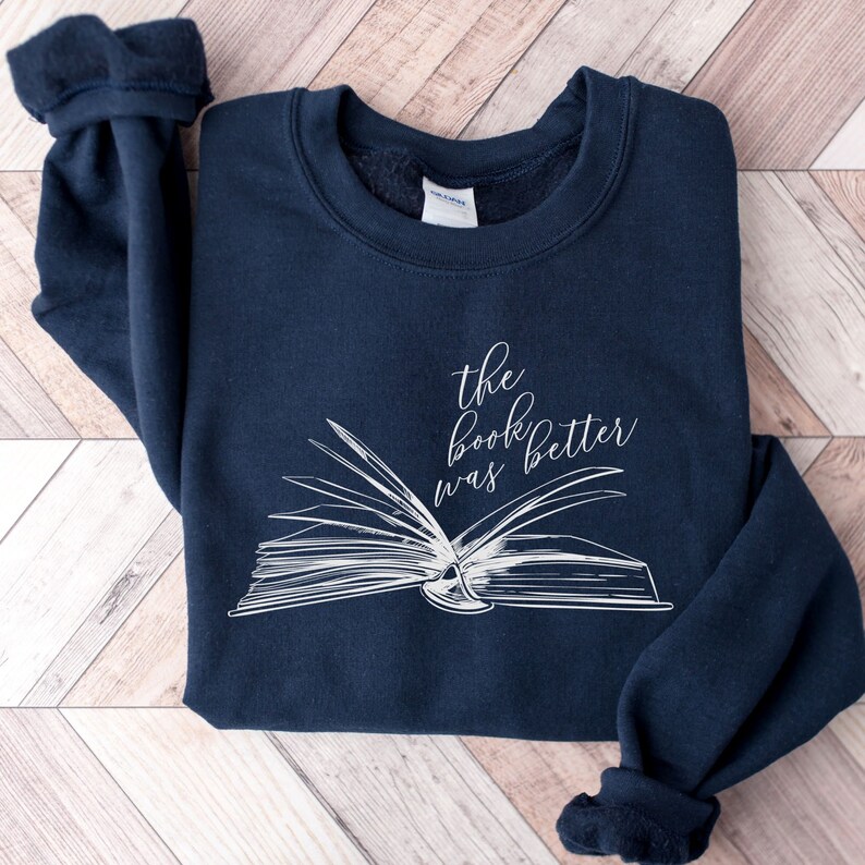 May include: A navy blue sweatshirt with a white graphic of an open book and the text "the book was better".