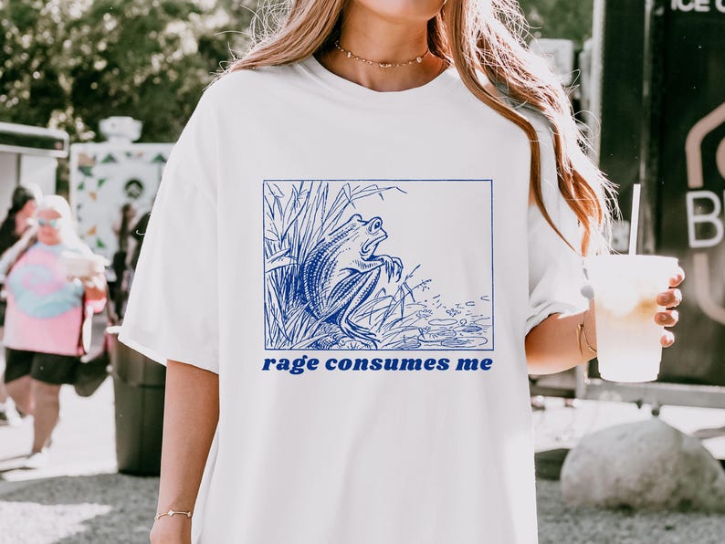 May include: White t-shirt with a blue graphic of a frog in a pond and the text "rage consumes me".