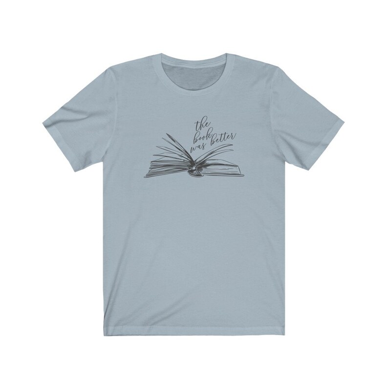 May include: Light blue t-shirt with a black and white illustration of an open book. The text "the book was better" is written above the book.