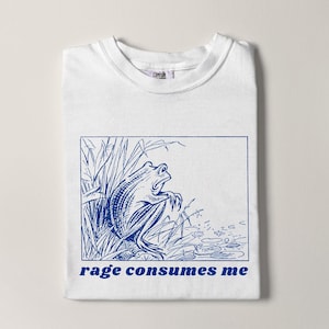 May include: White t-shirt with a blue line drawing of a frog in a pond with the text "rage consumes me" printed in blue.