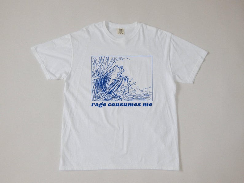 May include: White t-shirt with a blue illustration of a frog in a pond and the text "rage consumes me".