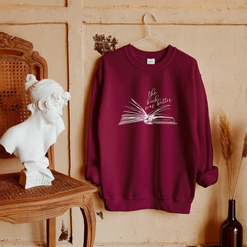 May include: Burgundy sweatshirt with a white graphic of an open book and the text "The book was better".