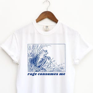 May include: White t-shirt with a blue illustration of a frog in a pond and the text "rage consumes me" printed on the front.