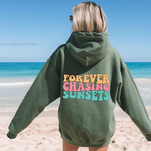 May include: A green hooded sweatshirt with the text "FOREVER CHASING SUNSETS" in colorful, retro-style lettering on the back.