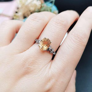 Pode incluir: Um anel de prata com uma grande gema oval de topázio. O anel tem um design delicado e intrincado com pequenos diamantes que circundam a pedra central.