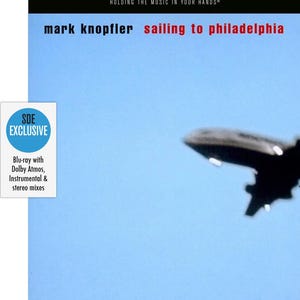 May include: Blu-ray disc cover for "Sailing to Philadelphia" by Mark Knopfler. The cover features a blurred image of an airplane against a light blue sky. Text includes "SDE SURROUND SERIES" and "SDE EXCLUSIVE".