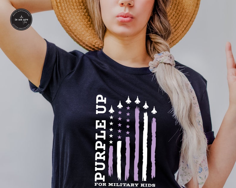 May include: A black t-shirt featuring a purple and white American flag design. The flag has white stars and white stripes with a purple stripe on the right side. The text "Purple Up" is written vertically on the left side of the flag and the text "For Military Kids" is written below the flag.
