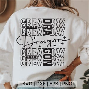 May include: White sweatshirt with a black graphic design. The design includes the word "Dragon" in a script font, surrounded by the words "Great Day" and "It's a Great Day". The bottom of the sweatshirt has the words "To Be A Great Day".