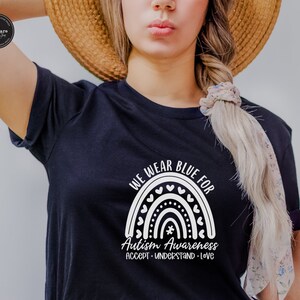 May include: A black t-shirt with a white rainbow design and the text "We wear blue for Autism Awareness Accept - Understand - Love".