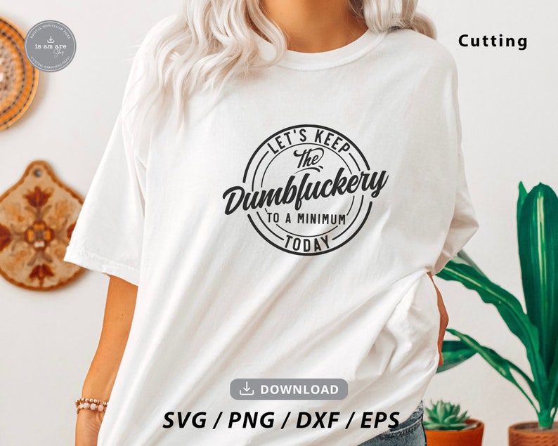 May include: White t-shirt with a black circle graphic that says "Let's Keep The Dumbluckery To A Minimum Today".
