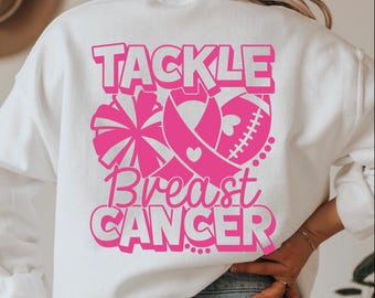 May include: White sweatshirt with a pink graphic design that says "Tackle Breast Cancer". The graphic includes a pink ribbon, a football, and a cheerleader's pom-pom.