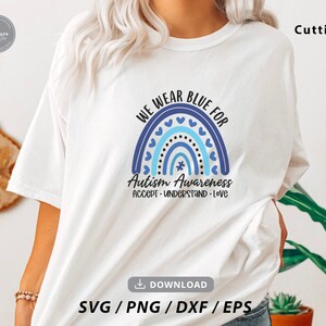 May include: A white t-shirt with a blue and white rainbow design and the text "We Wear Blue For Autism Awareness Accept Understand Love".