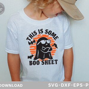 May include: White t-shirt featuring a Halloween-themed graphic. The design includes a black ghost wearing sunglasses, bats, and the text "THIS IS SOME BOO SHEET" in black and orange. The shirt is for digital download.