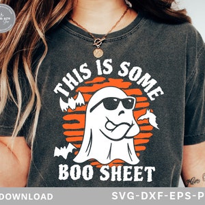 May include: Dark gray t-shirt with a Halloween-themed graphic. The design features a white ghost wearing sunglasses, with the text "THIS IS SOME BOO SHEET" in white and orange. Bats are also included in the design.