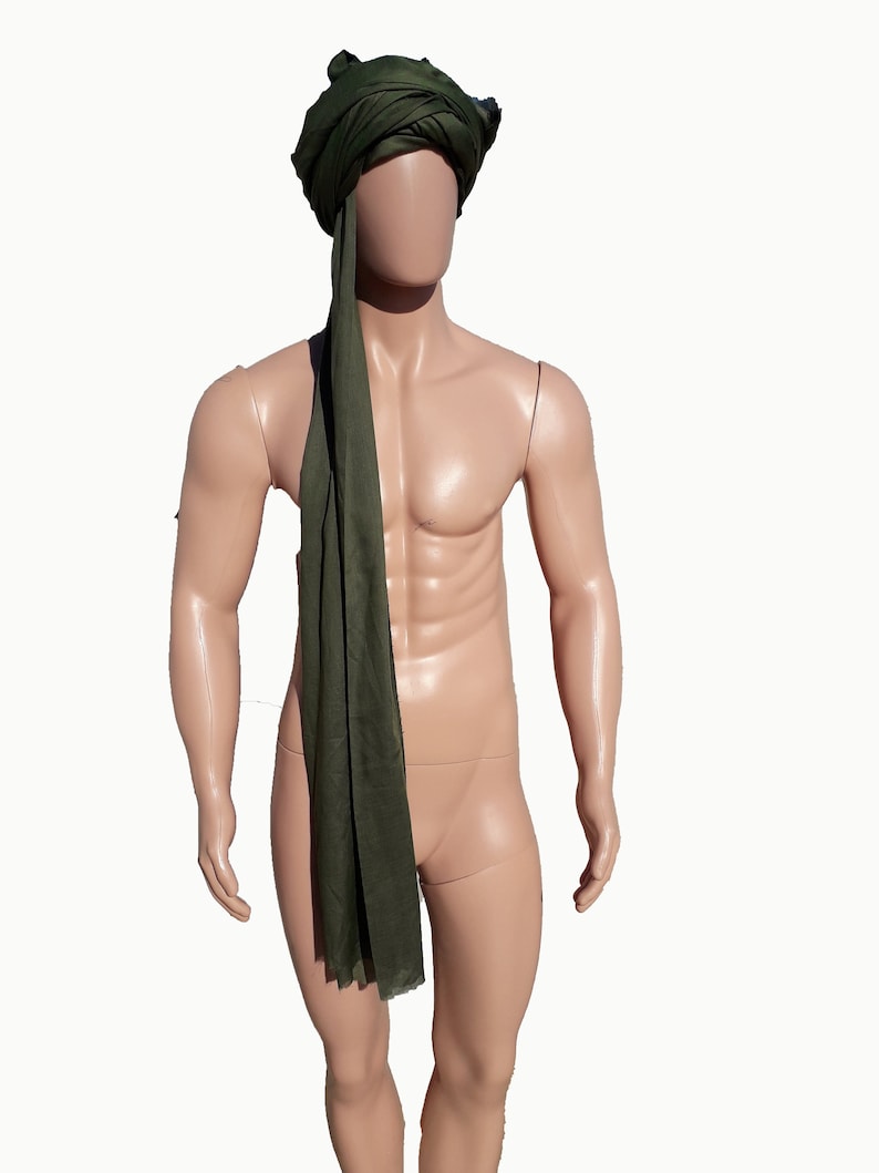 May include: A green turban with a long tail, worn by a mannequin.