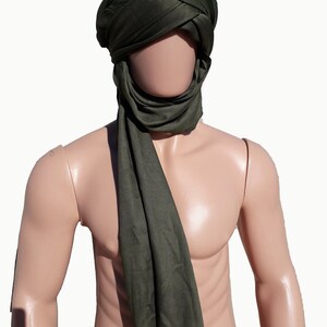 May include: A dark green headscarf with a long scarf attached. The scarf is draped around the neck and shoulders.