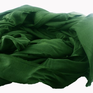 May include: A deep green fabric scarf is folded and bunched up, creating a soft, textured look.