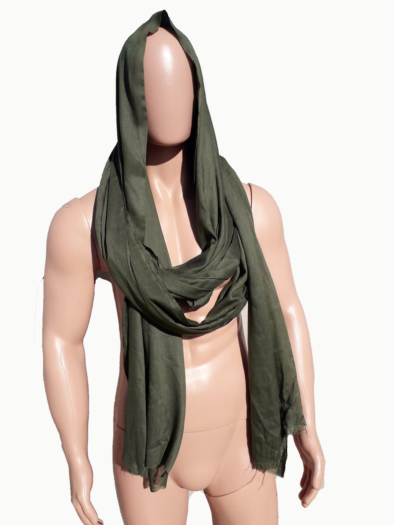 May include: A dark green scarf made of a soft, flowing fabric. The scarf is draped around a mannequin's neck and shoulders, creating a hooded effect.