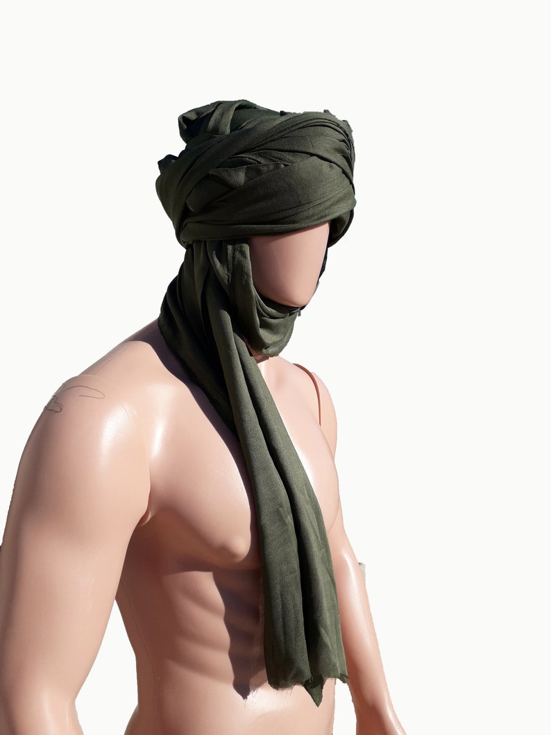 May include: A green fabric head covering, worn as a turban, with the ends draped down the front of the neck.