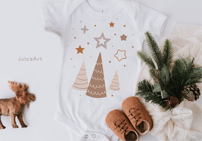 Puede incluir: Un body blanco para beb&eacute; con un dise&ntilde;o de &aacute;rbol de Navidad marr&oacute;n, rosa y blanco. El body tiene una estrella y peque&ntilde;os puntos en el fondo. El texto "JulzaArt" est&aacute; en la esquina superior izquierda.