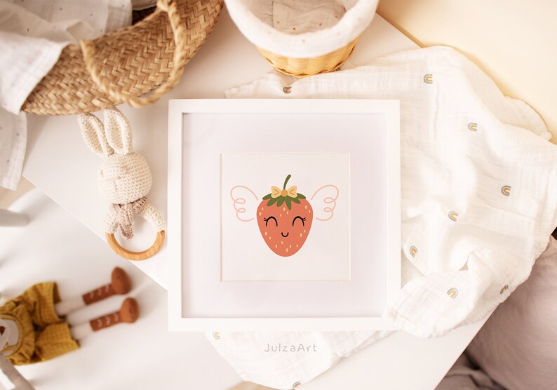 May include: A white framed print with a cute cartoon strawberry with wings and a bow. The strawberry is red with a green stem and yellow seeds. The background is white with a light pink border.