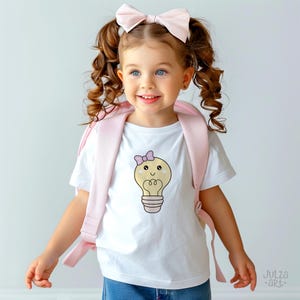May include: A young child wearing a white t-shirt with a cartoon lightbulb design and a pink bow. The child is also wearing a pink backpack and a matching bow in their hair. The image has the text "Julza art" in the bottom right corner.