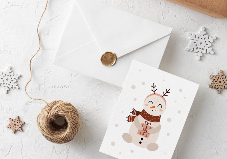 Pu&ograve; includere: Un biglietto bianco con una simpatica illustrazione di un pupazzo di neve che tiene un regalo. Il pupazzo di neve ha una sciarpa marrone, le corna e un viso rosa. Il biglietto ha uno sfondo bianco con puntini rosa e marroni.