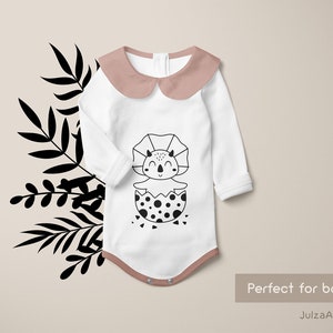 May include: White baby onesie with a pink collar and a black and white illustration of a dinosaur hatching from an egg. The text "Perfect for baby print" and "JulzaArt" are visible below the onesie.