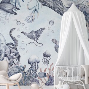 May include: A white canopy crib with a blue and gray watercolor mural featuring an octopus, stingray, jellyfish, and sea turtles. The mural is set against a light blue background with white bubbles.