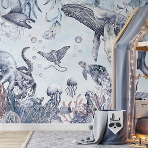 May include: A watercolor mural featuring a variety of sea creatures, including an octopus, a whale, a stingray, a turtle, and jellyfish. The mural is painted in shades of blue and gray and features a light blue background.