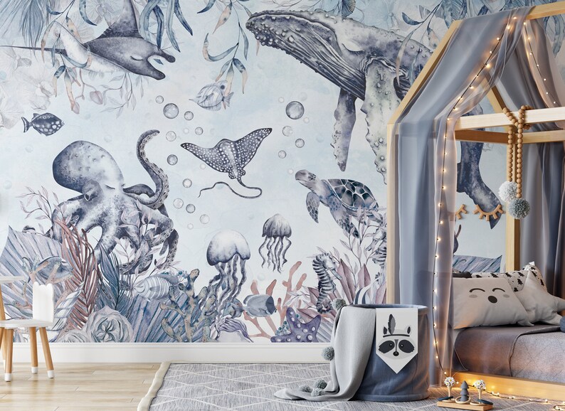 May include: A watercolor mural featuring a variety of sea creatures, including an octopus, a whale, a stingray, a turtle, and jellyfish. The mural is painted in shades of blue and gray and features a light blue background.