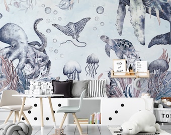 May include: A watercolor mural depicting an underwater scene with an octopus, a stingray, a turtle, jellyfish, and coral. The mural is painted on a light blue background with white bubbles. The mural is displayed in a child's room with a white table and chairs, a white bookshelf, and a white stuffed animal.