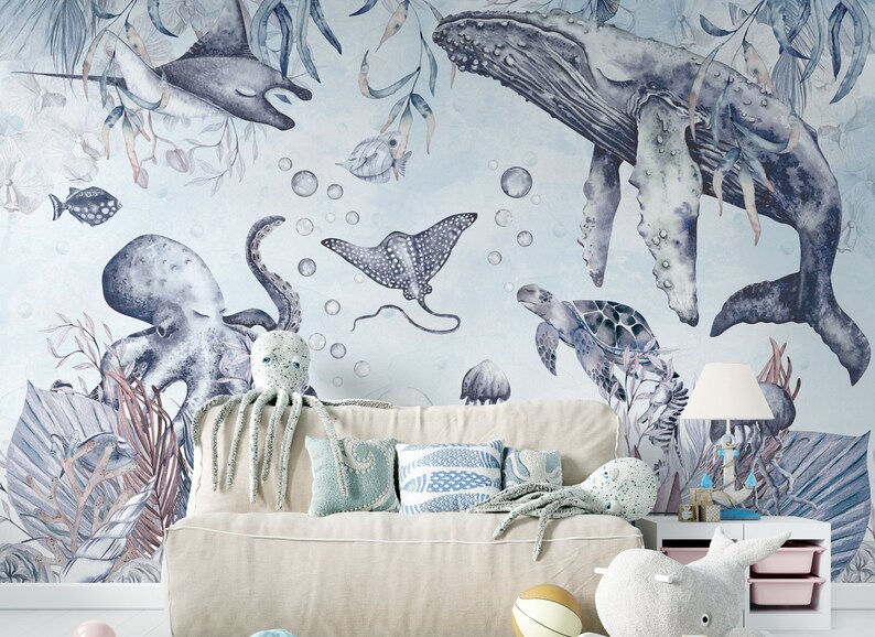 May include: A watercolor mural featuring a blue whale, octopus, stingray, and sea turtle. The mural is painted on a light blue background with white bubbles. The mural is displayed in a room with a white couch and pillows.