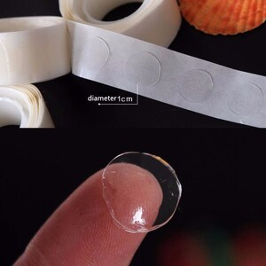 May include: Roll of clear adhesive dots with a diameter of 1 cm. The dots are on a white backing and are shown on a finger.