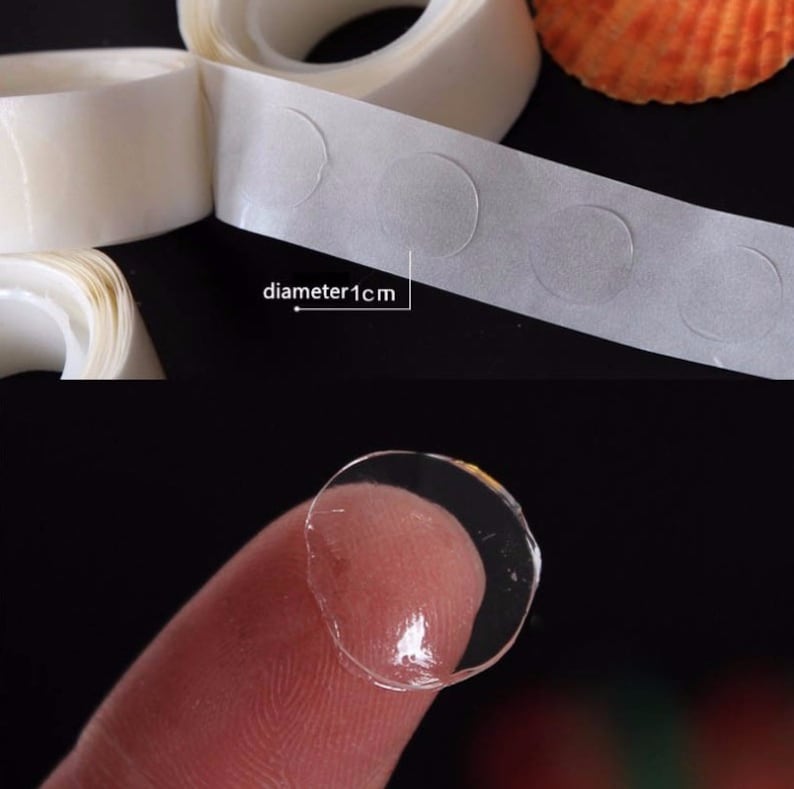 May include: Roll of clear adhesive dots with a diameter of 1 cm. The dots are on a white backing and are shown on a finger.