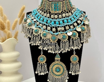 May include: A large, ornate gold and silver necklace with turquoise beads and coin accents. The necklace has a choker style and features a large pendant with a turquoise centre.