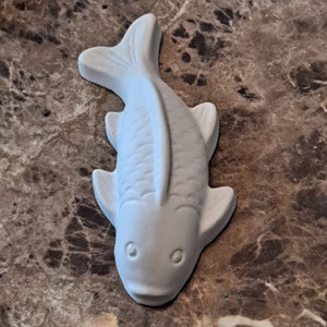 Puede incluir: Figurita de pez de cer&aacute;mica blanca con un dise&ntilde;o detallado. El pez tiene la boca ligeramente hacia arriba y ojos grandes.