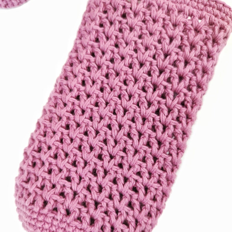 A close-up of a pink crocheted fabric with a textured pattern.