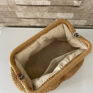 May include: A tan woven straw bag with a fabric lining and a metal clasp closure.