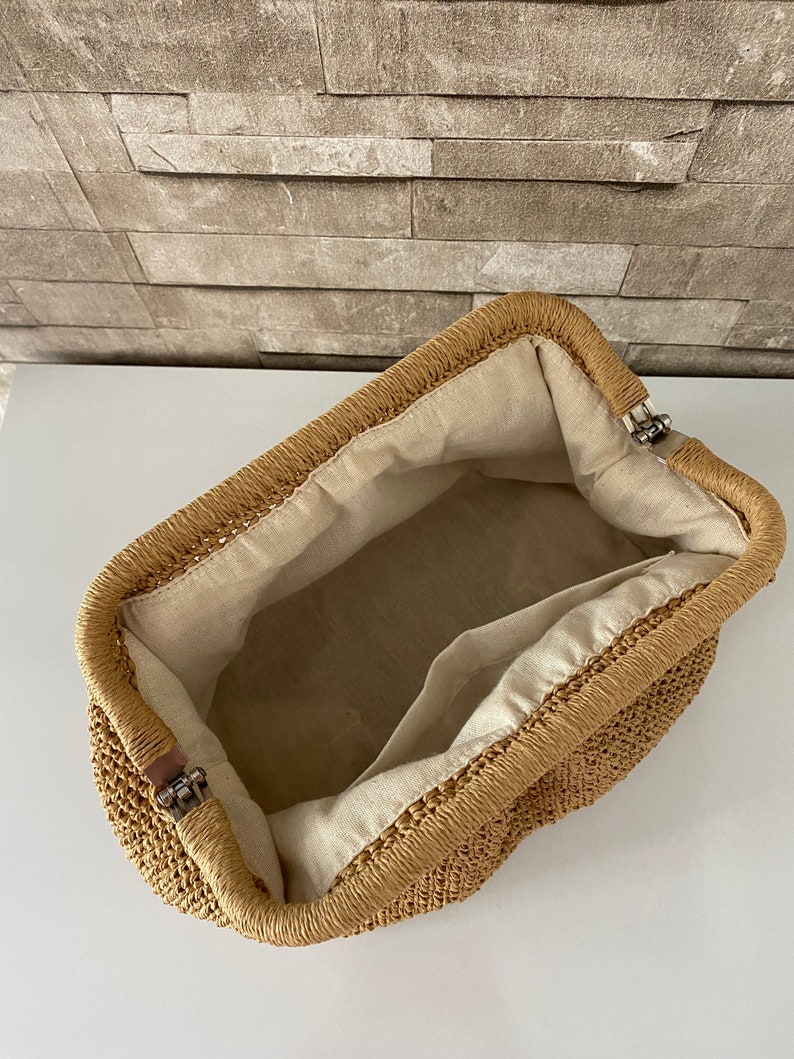May include: A tan woven straw bag with a fabric lining and a metal clasp closure.