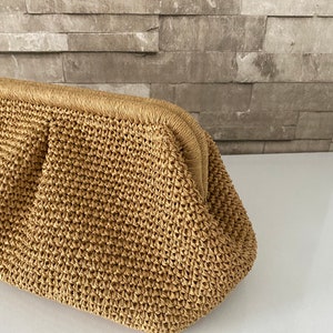 May include: A tan crocheted clutch bag with a rounded shape and a woven texture.