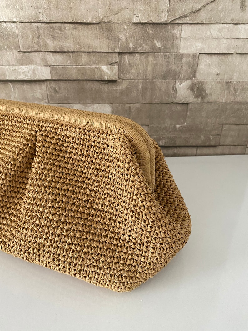 May include: A tan crocheted clutch bag with a rounded shape and a woven texture.