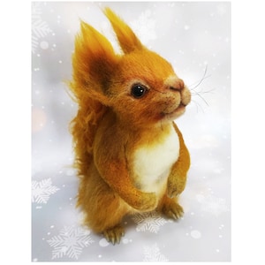 May include: A hand-crafted, needle-felted squirrel toy with a fluffy orange tail, white belly, and black eyes. The squirrel is standing on a white background with a snowflake pattern.