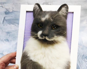 Pode incluir: Um gato cinza e branco com olhos amarelos é feltrado e emoldurado em uma moldura branca. O gato está sentado com as patas cruzadas e tem uma expressão séria.