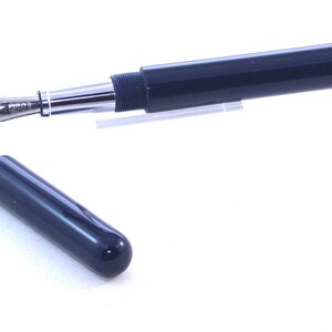 May include: A dark blue fountain pen with a silver trim and a cap. The pen is in a closed position and the cap is off.