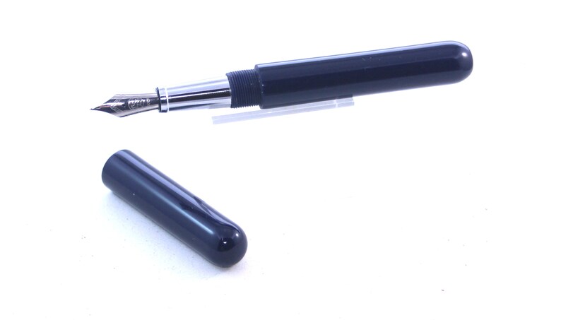 May include: A dark blue fountain pen with a silver trim and a cap. The pen is in a closed position and the cap is off.
