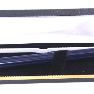 May include: A dark blue pen in a black velvet-lined box with a gold trim.