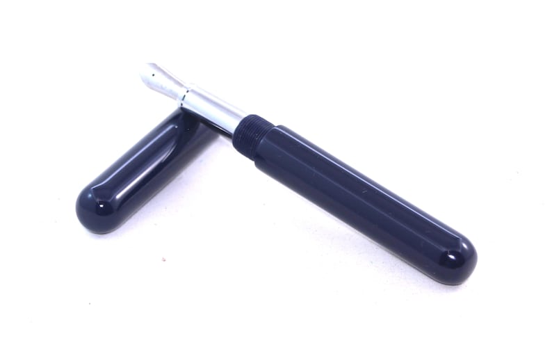 May include: A dark blue fountain pen with a silver nib and a cap. The pen is lying on a white surface.
