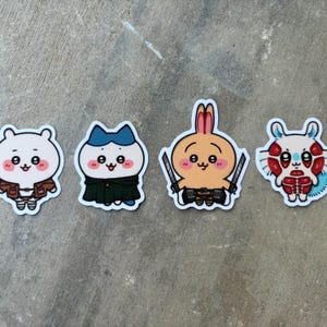 May include: Four cartoon stickers featuring cute animal characters. The stickers include a white bear in a brown jacket, a white cat in a green cape and blue hat, an orange bunny with swords, and a white and red creature.