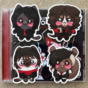 May include: Four die-cut stickers featuring cartoon characters with black hair and outfits, each with a different animal face. The stickers are placed on top of a CD case. The characters have pink cheeks and wear red ties.